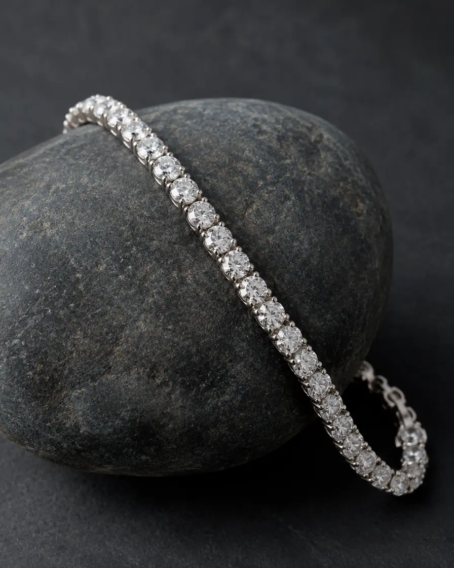 A white gold diamond tennis bracelet draped over a smooth stone